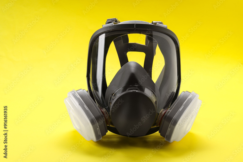 One full face respirator on yellow background, closeup One full face respirator on yellow background, closeup