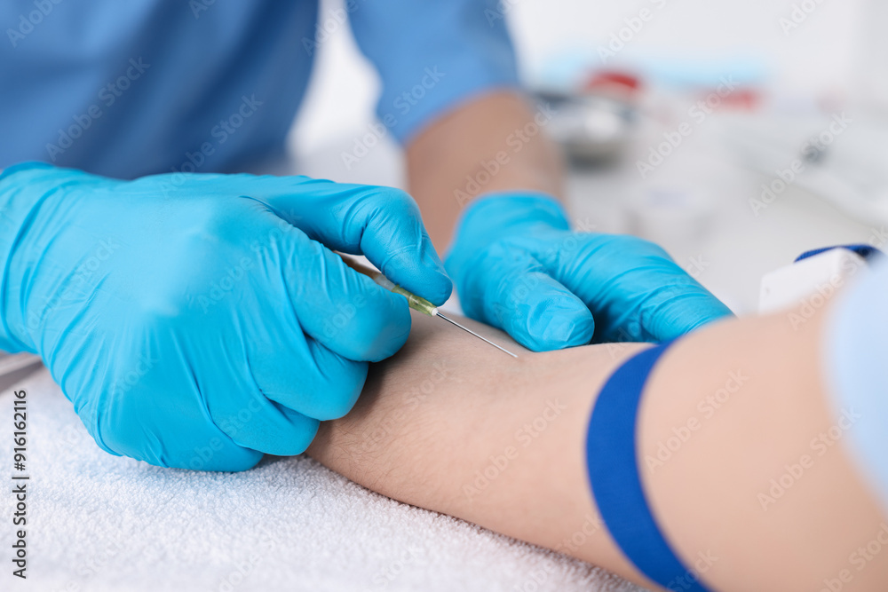 Nurse inserting IV into arm of patient in hospital, closeup Nurse inserting IV into arm of patient in hospital, closeup