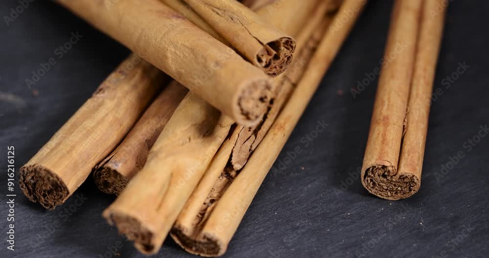 Thick wooden cinnamon on a black slate board, cinnamon spices close-up before grinding