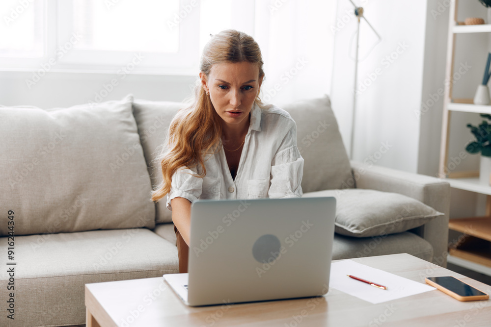 Woman relaxing on couch while browsing laptop on coffee table in cozy living room setting Woman relaxing on couch while browsing laptop on coffee table in cozy living room setting