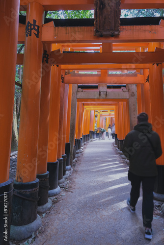 Red pagodas and gates up the mountain in Fushimi Inari-Taisha shinto shrine temple in Kyoto, Japan with traditional architecture buildings, buddha and fox statues decorations and Japanese garden photo