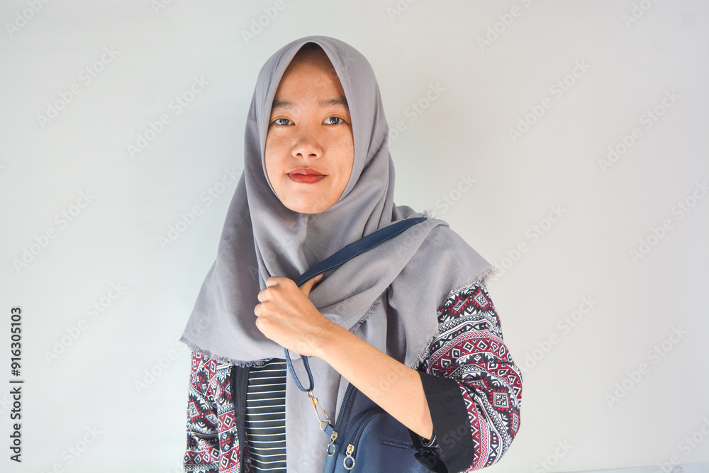 Portrait of a young Indonesian woman carrying a bag and raising her thumb confidently at the camera Portrait of a young Indonesian woman carrying a bag and raising her thumb confidently at the camera