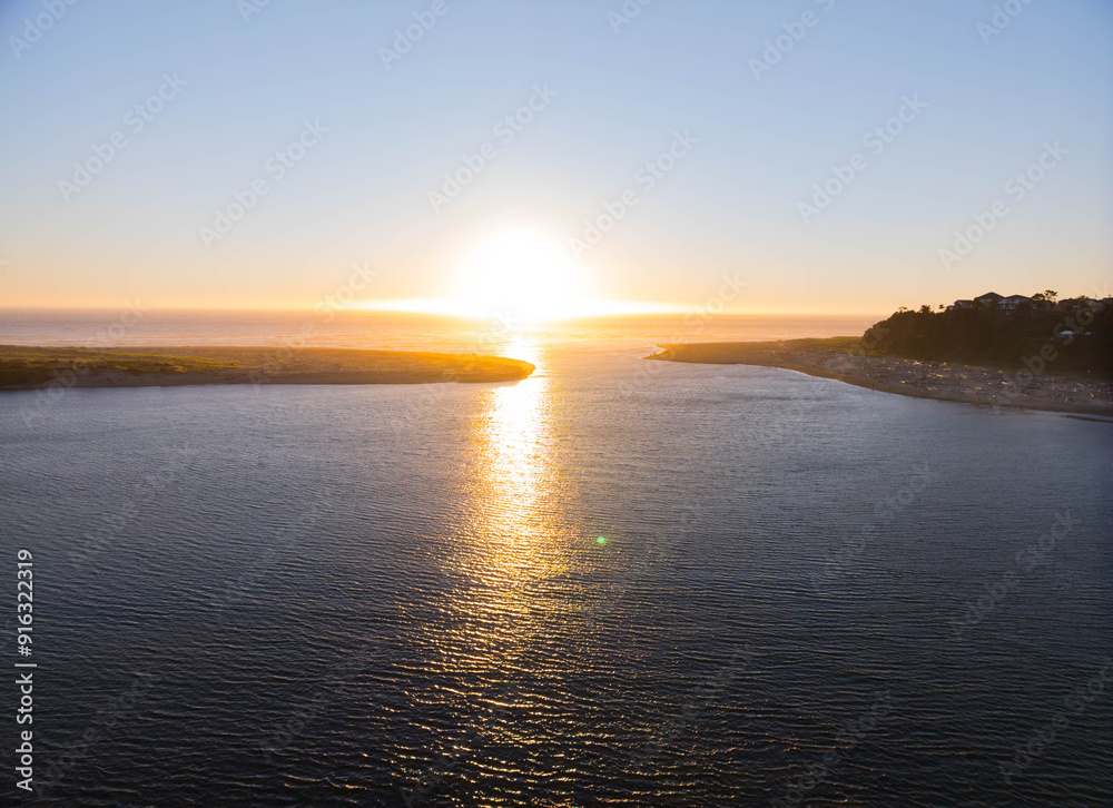 Obraz premium The sun is setting over the water, creating a beautiful and serene atmosphere