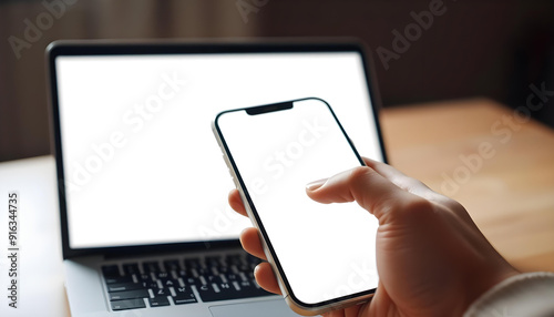 Person Holding Smartphone with Laptop in Background