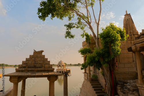 Chhatris and shrines of hindu Gods and goddesses at Gadisar lake, Jaisalmer, Rajasthan, India. Indo-Islamic architecture , sun set and colorful clouds in the sky with view of the Gadisar lake. photo