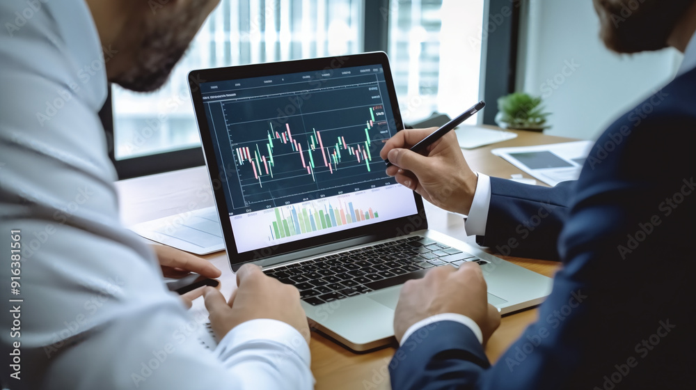 Two business men looking at financial data on their laptops and holding an iPad with stock market charts. Two business men looking at financial data on their laptops and holding an iPad with stock market charts.