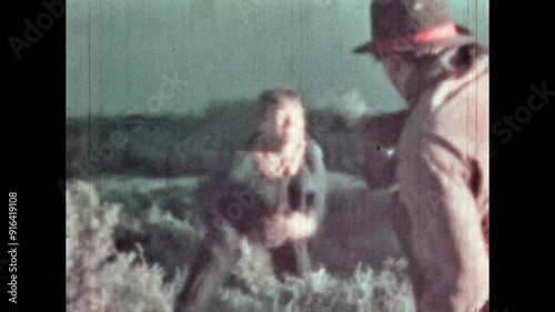 Cowboy shooting man on green hill. Tragic scene from adventure western film in nature outdoor. Cinematic shoot death in wild west,. Villain killing movie hero. Vintage color archive. Retro 1960s