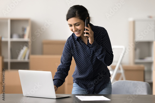 Photography Indian female, warehouse worker using laptop while talking on phone, managing in