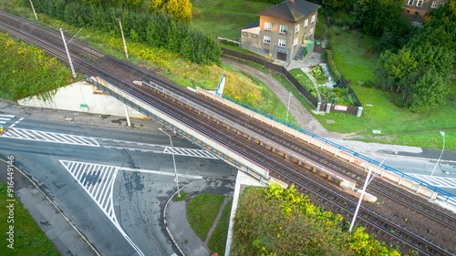 Aerial view of a railway crossing near a residential area surrounded by greenery in the afternoon