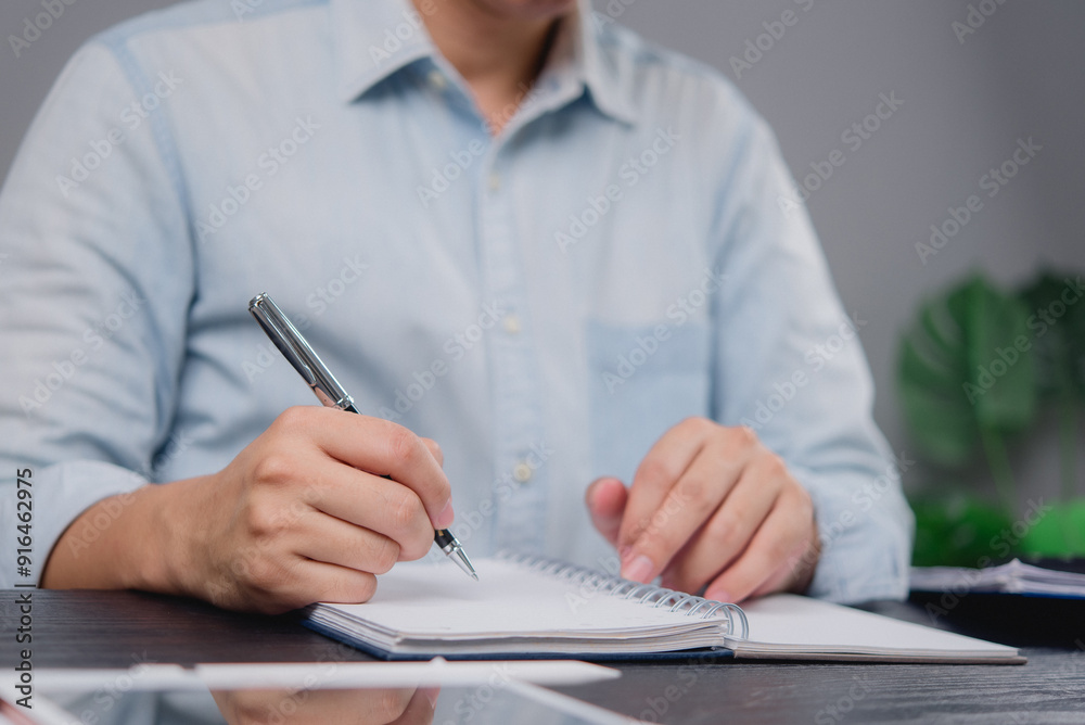 Business professional writing notes in a notebook. Ideal for themes around planning, strategy, or workplace organization in business environments.