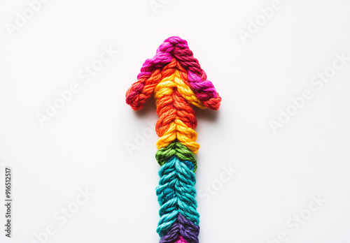 Colorful yarn arrow pointing upwards on white background, symbolizing growth