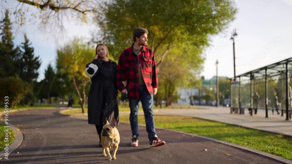 A couple walks with their dog in a park during autumn, enjoying the serene landscape and bonding A couple walks with their dog in a park during autumn, enjoying the serene landscape and bonding
