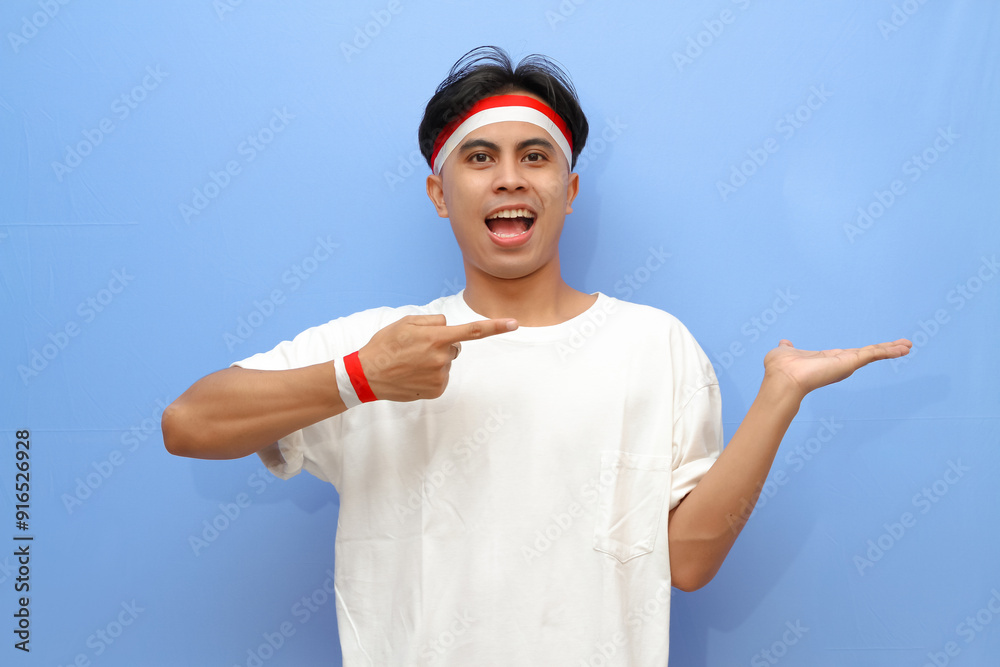 Indonesian man in white shirt and Indonesian flag posing pointing to the his open hand palm with happy excited face,Indonesian independence day concept Indonesian man in white shirt and Indonesian flag posing pointing to the his open hand palm with happy excited face,Indonesian independence day concept