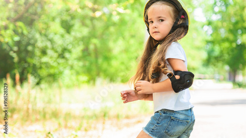 Girl skateboard with safety equipment - helmet, knee and elbow pads. Safe summer activity. Kids activity.