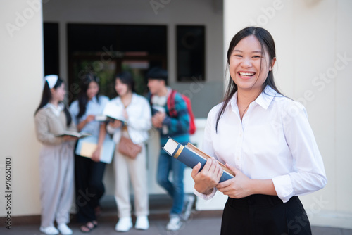 Smiling student holding book on campus photo