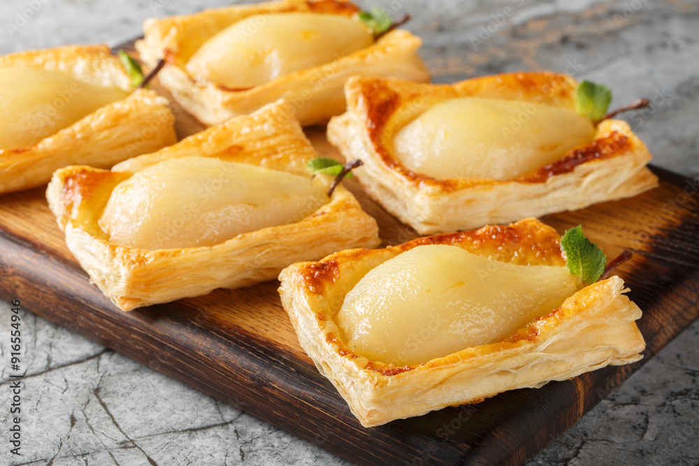 Caramelized pears baked in puff pastry and stuffed with nuts and cream cheese close-up on a wooden board. Horizontal Caramelized pears baked in puff pastry and stuffed with nuts and cream cheese close-up on a wooden board. Horizontal