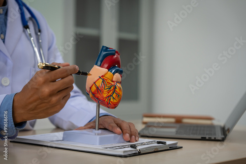 Fotografija A male doctor sits at a desk in the heart clinic, consulting online and giving advice