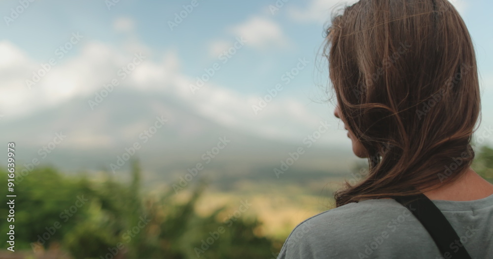 Woman stands near towering mountain, enjoy view on Legazpi Mountains Volcano, Philippines. Asia wild nature tropical landscape. Tourist female relax outdoor lifestyle travel on summer holiday vacation Woman stands near towering mountain, enjoy view on Legazpi Mountains Volcano, Philippines. Asia wild nature tropical landscape. Tourist female relax outdoor lifestyle travel on summer holiday vacation