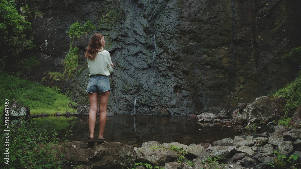 Young woman enjoying a hidden waterfall in a lush tropical forest, seeking tranquility in french polynesia's moorea Young woman enjoying a hidden waterfall in a lush tropical forest, seeking tranquility in french polynesia's moorea