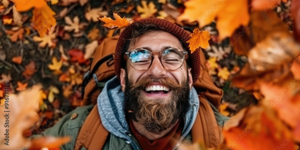 Handsome bearded man lying down smiling surrounded by autumn leaves Handsome bearded man lying down smiling surrounded by autumn leaves