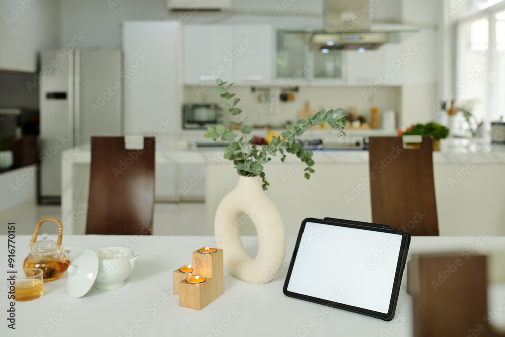 Dining table with candles, plant and digital tablet in modern kitchen Dining table with candles, plant and digital tablet in modern kitchen