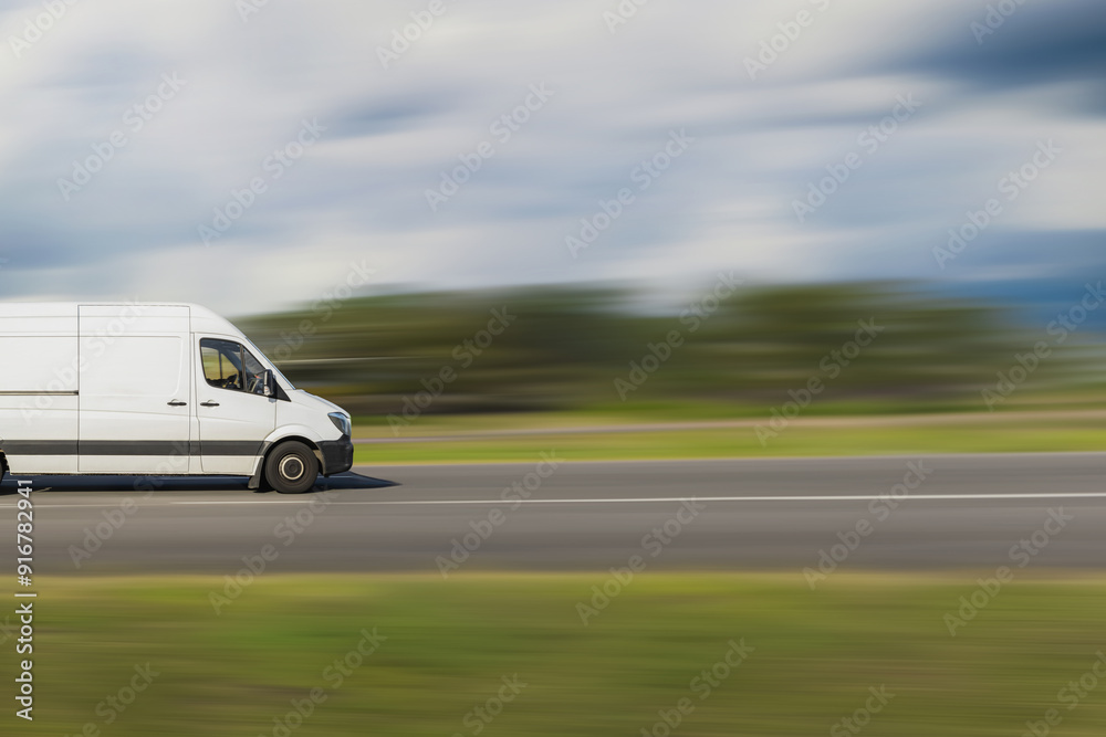 Cargo van on a blurred background. White cargo van driving down the street with a speed blur background. Transportation, logistics concept with free space for text, copy space Cargo van on a blurred background. White cargo van driving down the street with a speed blur background. Transportation, logistics concept with free space for text, copy space