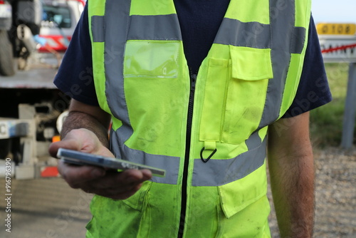 Homme avec gilet jaune et smartphone à la main photo