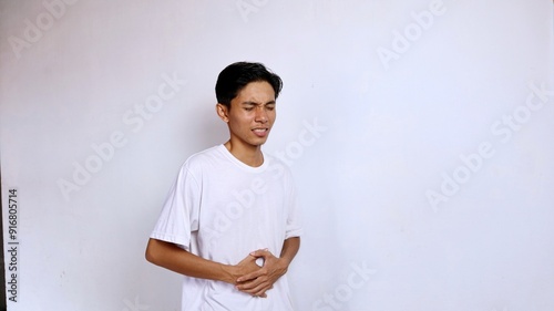 Young Asian man wearing white shirt sick in stomach area hand gesture holding stomach isolated white background photo