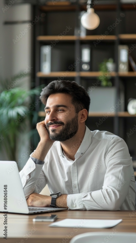 A man is sitting at a desk with a laptop and smiling A man is sitting at a desk with a laptop and smiling