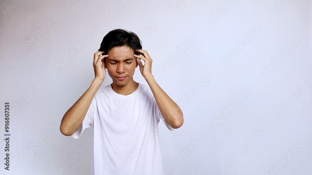 Asian young man wearing white shirt gesture hand holding head . headache Asian young man wearing white shirt gesture hand holding head . headache