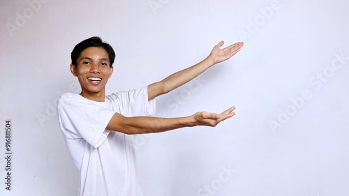 happy young asian man posing showing copy space on the side with both hands photo