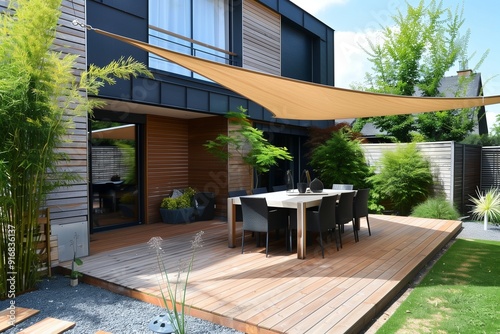 Contemporary terrace with a wooden dining setup and a triangular shade sail.