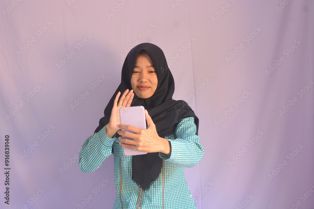 Portrait of an Asian woman holding a smartphone while smiling at the camera and raising her hand showing an okay gesture. on an isolated background Portrait of an Asian woman holding a smartphone while smiling at the camera and raising her hand showing an okay gesture. on an isolated background