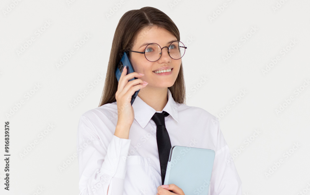 Joyful european woman in white shirt is speaking on the phone with classmates friends while smiling preparing to go to University High school holding tablet in hand. Joyful european woman in white shirt is speaking on the phone with classmates friends while smiling preparing to go to University High school holding tablet in hand.