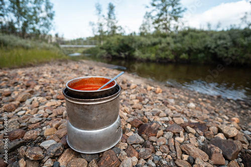 A outdoor cooker with delicious tomato soup for lunch break during outdoor hiking adventure in Swedish Lapland Padjelanta National Park. Background blurred in creamy bokeh. photo