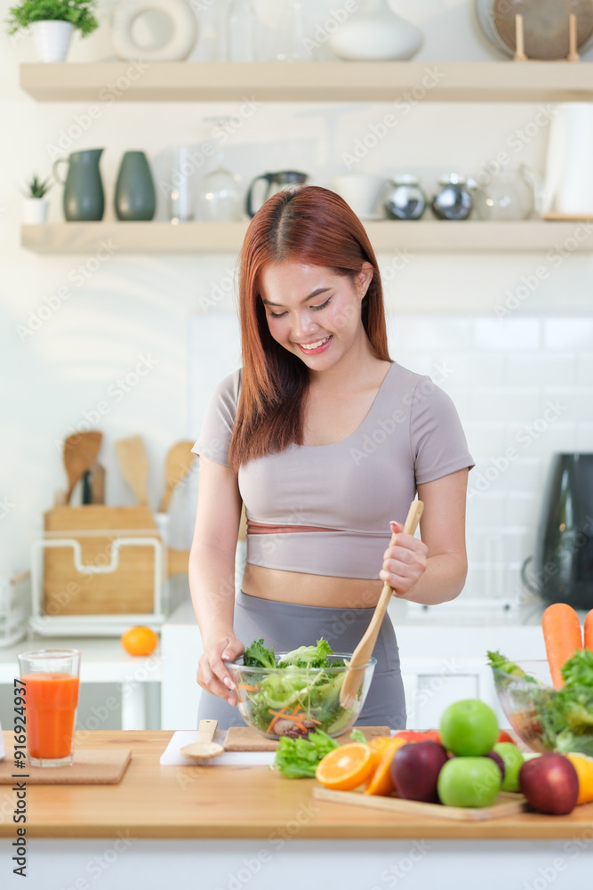 A young woman in athletic wear smiles while preparing a fresh salad in a bright, modern kitchen. A young woman in athletic wear smiles while preparing a fresh salad in a bright, modern kitchen.