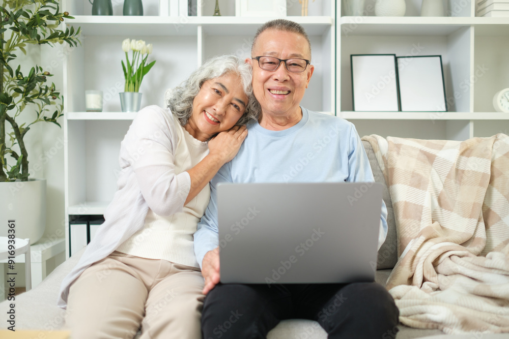 Affectionate elderly couple sitting closely together on a comfortable sofa with laptop. Affectionate elderly couple sitting closely together on a comfortable sofa with laptop.