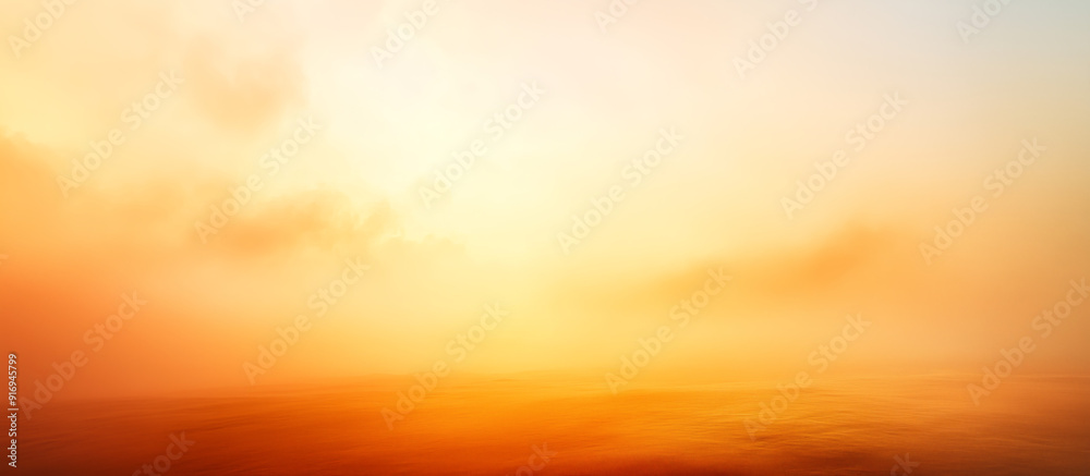 A soft, orange gradient illuminates a blurred, foggy landscape, capturing the essence of a serene sunrise or sunset.