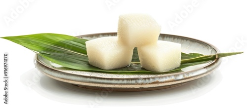 Two zongzies a Chinese dessert displayed on a plate with fresh bamboo leaf set against a plain white background for a copy space image photo