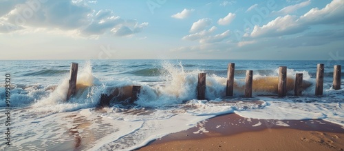 Fototapeta Naklejka Na Ścianę i Meble -  Seascape with wooden wave breakers on the beach capturing a serene setting with ample copy space image