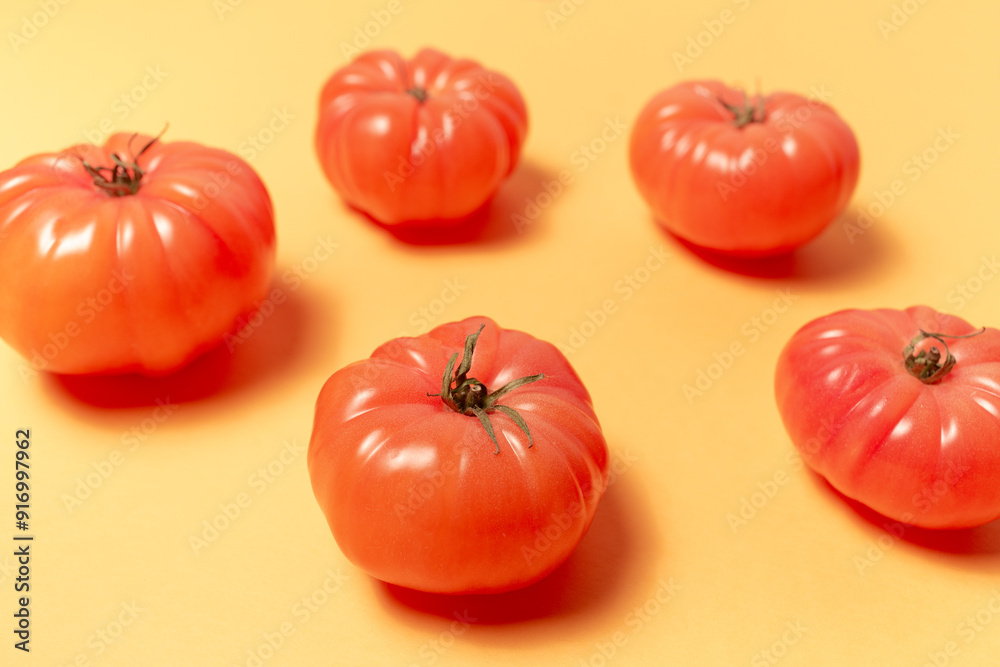 Close-up of pink tomatoes on background of pastel yellow color. Top view. Colourful pattern. Close-up of pink tomatoes on background of pastel yellow color. Top view. Colourful pattern.