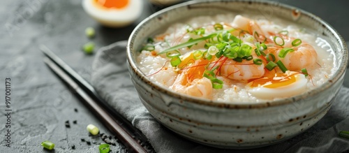 Delicious shrimp porridge topped with eggs and fresh spring onions served in a bowl with a generous helping a mouthwatering dish with copy space image