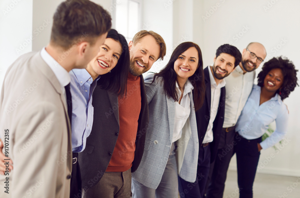 Cheerful business multiethnic people men and women standing in a row in office and smiling. Company employees or group of staff hugging and talking on a meeting. Team work concept. Cheerful business multiethnic people men and women standing in a row in office and smiling. Company employees or group of staff hugging and talking on a meeting. Team work concept.