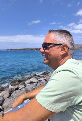 Portrait of a young adult man in profile,standing,looking at the sea.Young tourist in profile dreaming in front of the ocean. Lonely boy looking at the sea relaxing.Profile of a man looking at the sea
