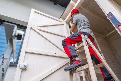 Wallpaper Mural Man Repairing Wooden Door While Standing on a Ladder in a Residential Setting Torontodigital.ca