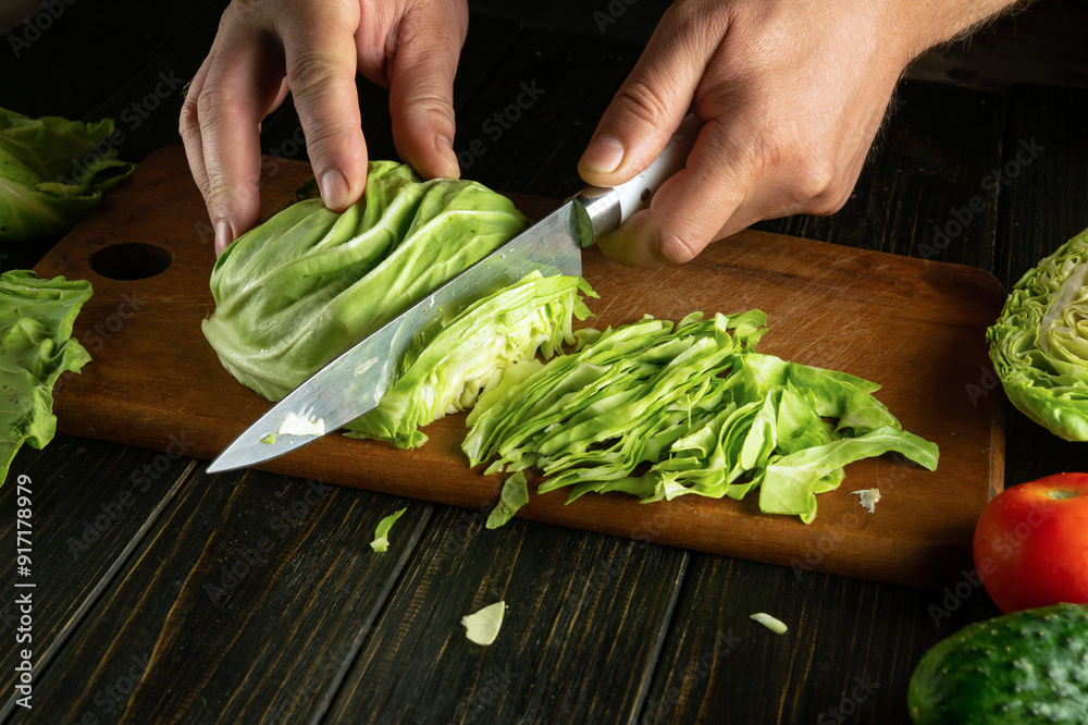 Fotografie Chef chops fresh cabbage with a knife to prepare dinner