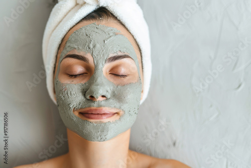 A woman relaxes with a green clay mask on her face, showcasing self-care and beauty routine in a serene setting.