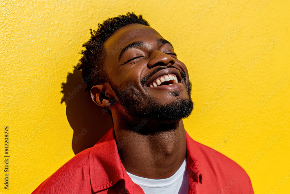 Close-Up Portrait of a Smiling Black Man in Red and White Outfit, Radiating Happiness on a Sunny Day with Yellow Wall as Backdrop Close-Up Portrait of a Smiling Black Man in Red and White Outfit, Radiating Happiness on a Sunny Day with Yellow Wall as Backdrop