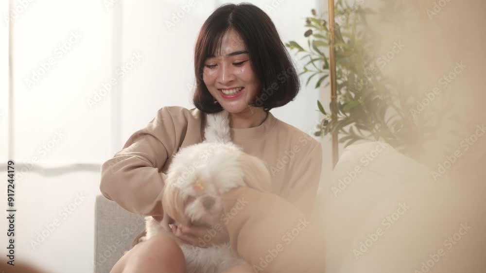 Happy young asian woman cuddling and spending time with cute dog in living room. Happy young asian woman cuddling and spending time with cute dog in living room.