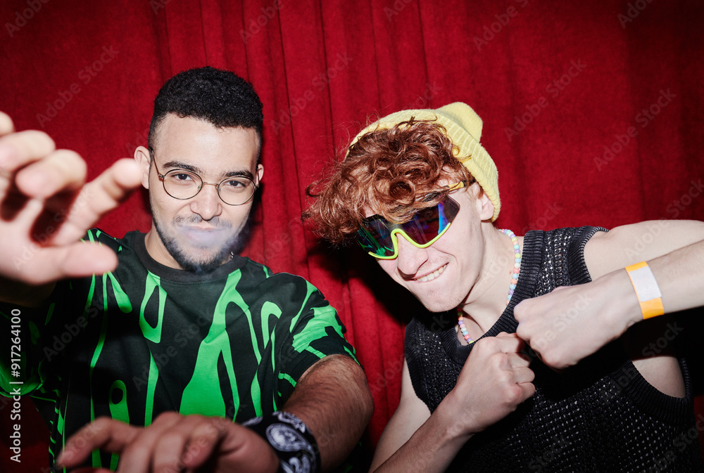 © pressmaster - Young intercultural men in funky apparel standing and posing in front of camera against deep red curtains in night club © pressmaster - Young intercultural men in funky apparel standing and posing in front of camera against deep red curtains in night club